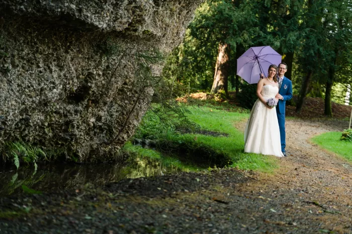Nicht vergessen am Hochzeitstag: Ein Sonnen- und Regenschirm schützt das Brautpaar beim Paarshooting draussen.